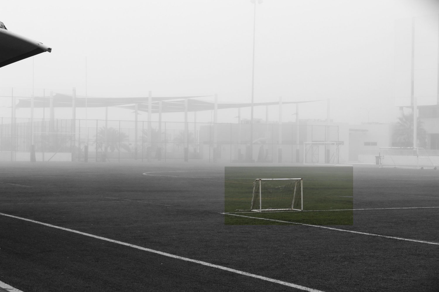 A goal on a fogbound pitch, desaturated except for a rectangle of colour around the goal